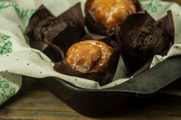 Poster - Homemade chocolate and vanilla cupcakes on a wooden table, sprinkled with powdered sugar. Breakfast