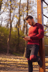 Wall Mural - Man chatting online using smart phone while taking a workout break