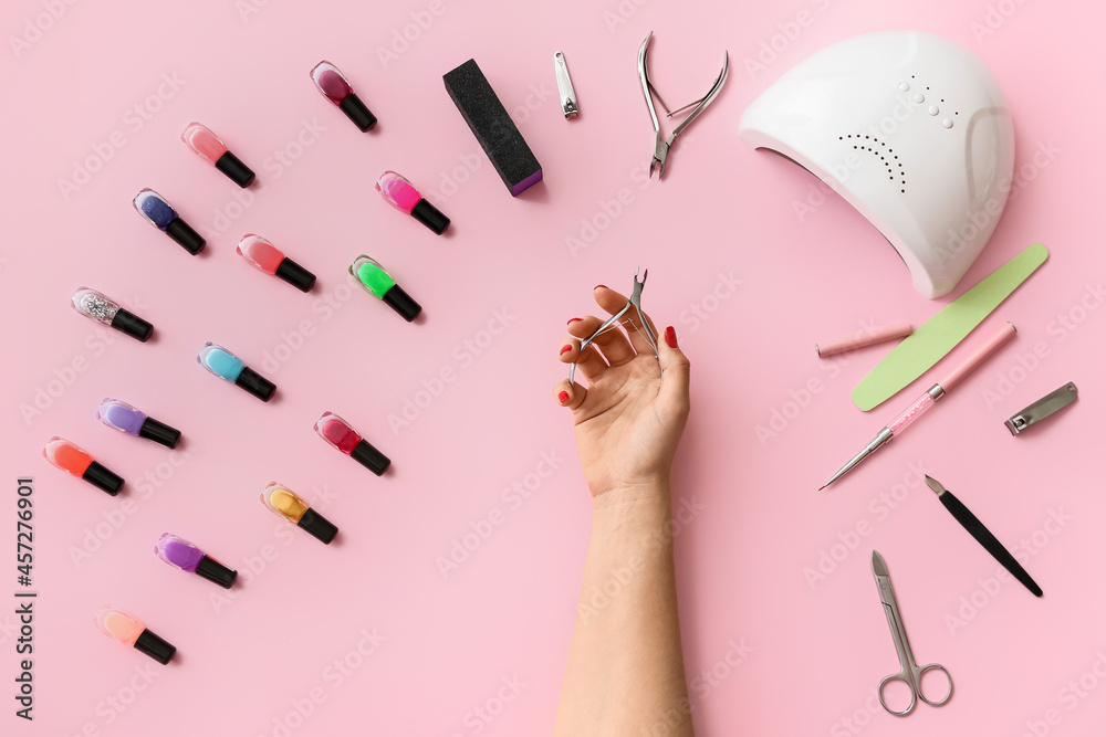 Female hand with manicure cutter and tools on color background