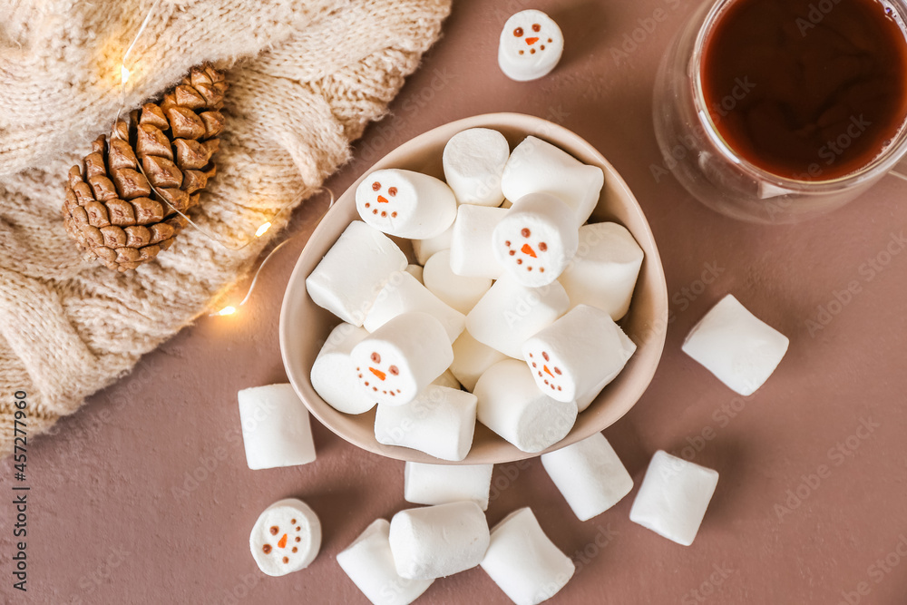 Bowl with snowmen made of soft marshmallows on color background