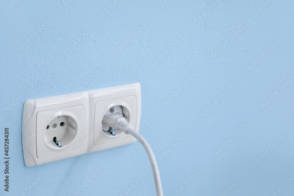 Electric socket with plug on color wall