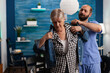 © DC Studio - Social asisstant man worker helping pensioner disabled senior woman puts jacket during recovery session. Healthcare assistance. Social services nursing elderly retired woman. Disability people support
