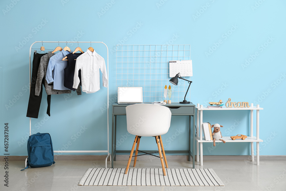 Workplace and rack with school uniform in interior of room