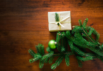 Sticker - Christmas gift box with Christmas tree branch decor and gold ribbon on a wooden brown background. Lights, Christmas balls. copy space. Recycled paper has been used.