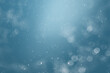 blurred abstract background with bokeh and snowflakes in the air on a blue background