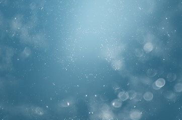 Wall Mural - blurred abstract background with bokeh and snowflakes in the air on a blue background