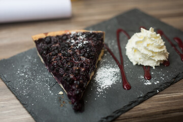 Sticker - Closeup of blueberry pie and chantilly cream on chalk on the table of restaurant terrace in outdoor