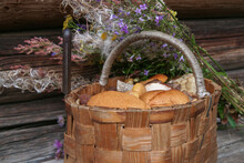 Composition With A Basket Full Of Mushrooms And Wildflowers On A Natural Wooden Background.