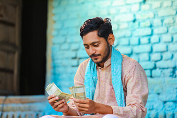 Wall Mural - Happy Indian farmer counting money at home.