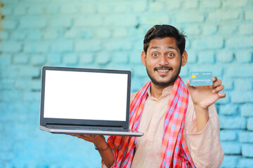 Wall Mural - Indian farmer showing laptop screen and card at home