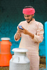 Canvas Print - Young indian milkman using smartphone