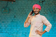 © PRASANNAPIX - Indian farmer talking on smartphone at home.