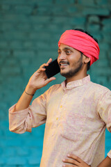 Wall Mural - Indian farmer talking on smartphone at home.