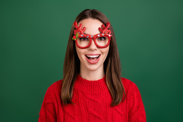 Wall Mural - Photo of young girl happy positive smile wear eyeglasses reindeer horns new year isolated over green color background