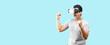 Asian man playing VR video game with virtual reality goggles and Shock and surprise face ,trying to touch something on light blue background in studio With copy space.