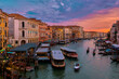 Sunset view of Grand Canal, Venice, Italy. Vaporetto or waterbus station, boats, gondolas moored by walkways, beautiful sunset clouds, UNESCO heritage
