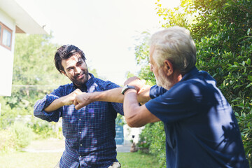 Wall Mural - Senior father and adult son playing together in the garden with happy and fun