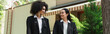 Interracial lesbian women in suits looking at each other in park, banner.