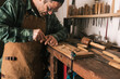 © Cavan Images - Side shot of a cabinetmaker working on a wood carving with a chisel.