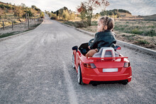 A Girl Riding A Toy Car