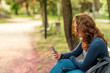 © Cavan Images - Portrait of charming red haired young woman with smartphone in a park