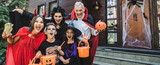 family in spooky costumes holding halloween attributes while growling at camera, banner