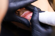 the permanent makeup artist performs the first pass of applying lip pigment