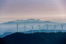 Wind Turbines On Mountain Against Sky During Sunset