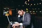 Fototapeta  - Successful businessman working on laptop during lunch break sitting in hotel restaurant, tired doing task