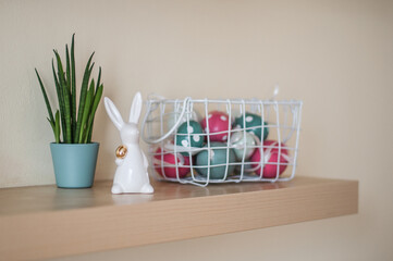 Wall Mural - Ceramic Easter Bunny with a golden egg in his arm and eggs in basket.