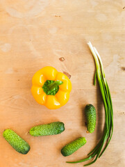 yellow bell-pepper, green onion and fresh cucumbers on a wooden table