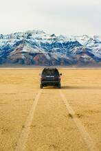 Car Parked On The Desert Playa With Mountain Peaks In The Distance