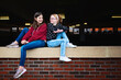 © Cavan Images - Two happy tween girls sitting on a brick wall together talking.