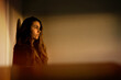 © Cavan Images - A woman standing in a bedroom watching the sunset from her window