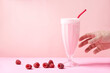 © Cavan Images - A hand grab a raspberry milkshake served in a glass with a reusable metal straw