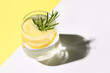 Glass of tasty lemon cocktail with rosemary on color background