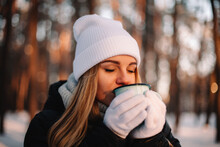 Woman holding cup enjoying hot drink outdoors during winter