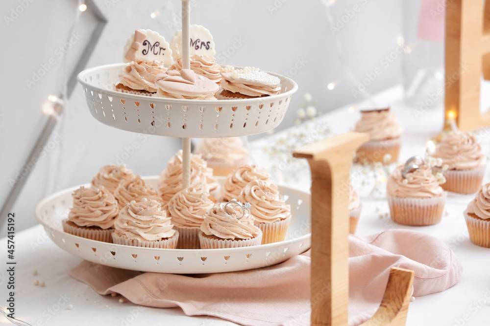 Dessert stand with tasty wedding cupcakes on table