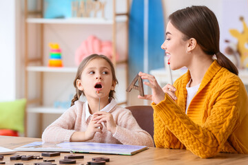 Wall Mural - Speech therapist working with cute girl in clinic