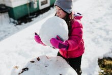 Young Girl Builds Snowman Outside While It's Snowing
