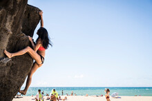 Tenacious Woman Scaling To The Top Of The Giant Rock At Waimea Bay