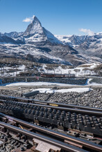 Scenic View Of Snowcapped Mountain Matterhorn And Cog Railway Tracks In Foreground And Blue Sky