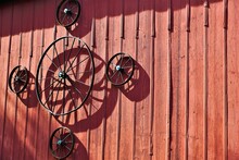 Antique Wagon Wheels Mounted On Side Of Red Barn.