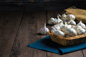 Wall Mural - A lot of garlic is put in a basket placed on a wooden table.