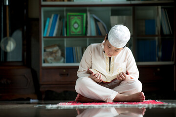 Wall Mural - A little Asian Muslim boy is sitting and reading the Quran. The peace in the mosque, with copy space.