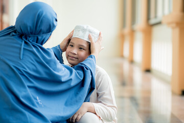 Wall Mural - Concept Eid Mubarak, A picture of an Islam Muslim boy chasing his mother with love, and the mother helped take care of his hat at the mosque after prayer.