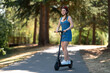 © Anton - A young active girl in a helmet is riding an electric scooter. Around the beautiful nature, large trees. A bright sunny day. Transport of the future, environmental protection.