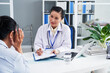 © DragonImages - General practitioner taking notes when talking to female patient suffering from severe headache