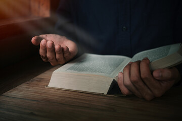 Wall Mural - Man is reading and praying the scripture or holy bible on a wooden table with copy space. Religion, believe Concept.