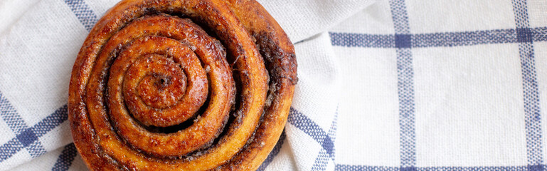 Wall Mural - banner of baked cinnamon buns on light background with checkered napkin